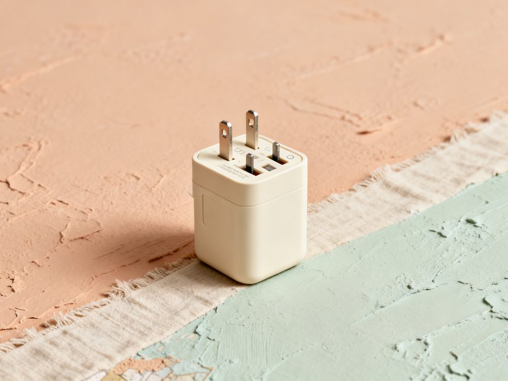 Adaptador de tomada universal de cor bege sobre fundo texturado verde e bege