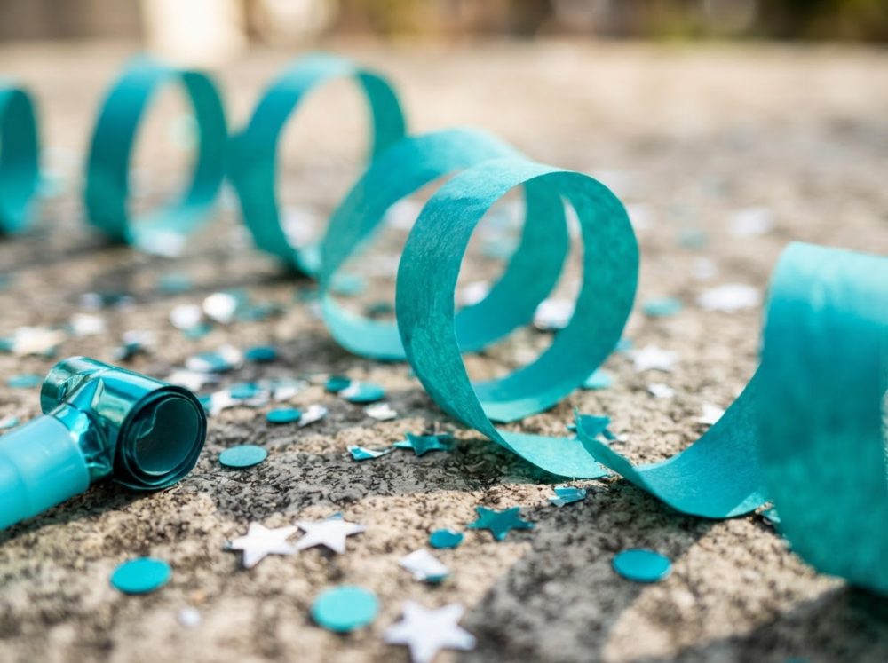 Serpentinas azuis e confetes redondos e de estrelas espalhados no chão.