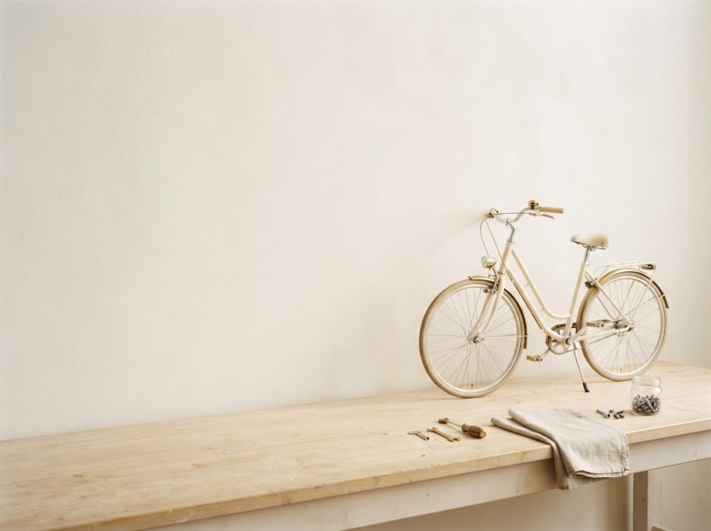 Bicicleta vintage creme sobre bancada de madeira com ferramentas e pano