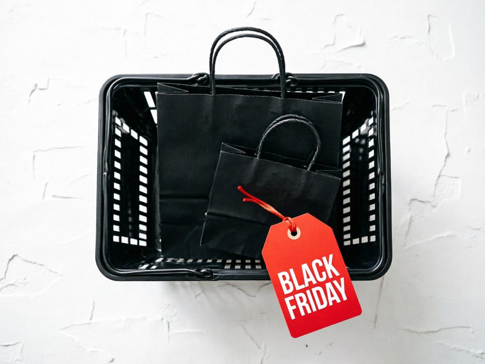 Cesto preto com sacos de papel e etiqueta vermelha com texto Black Friday