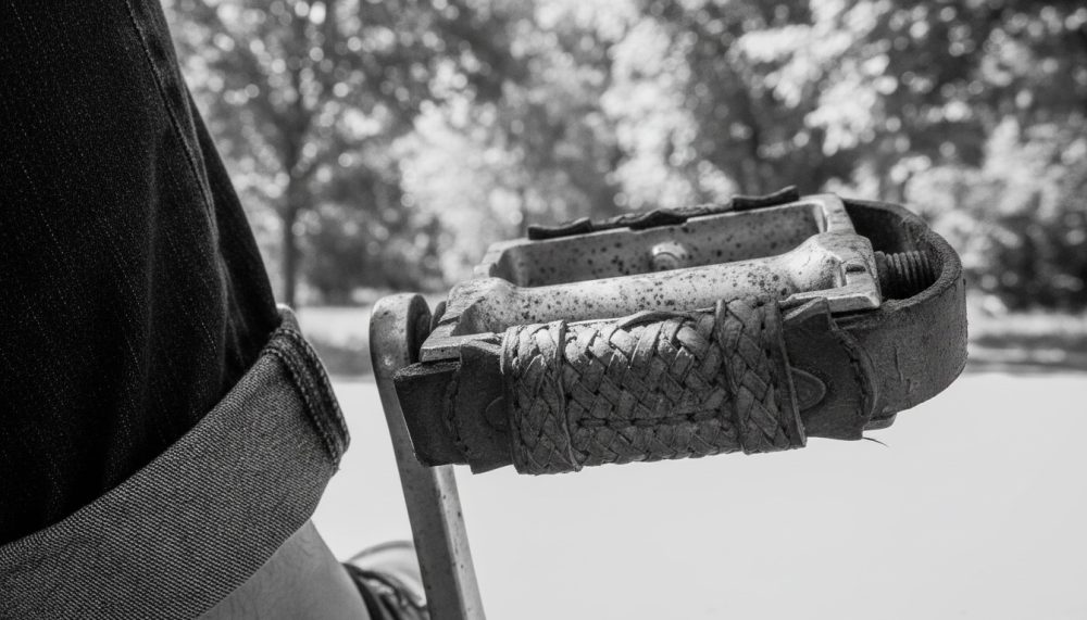 Pedal de bicicleta vintage em metal com capa de pele trançada com fundo de árvores desfocado