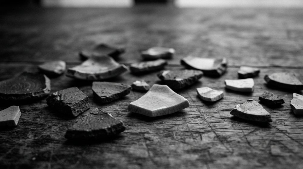 Fragmentos de cerâmica artesanal sobre superfície de madeira rústica destacando texturas e formas
