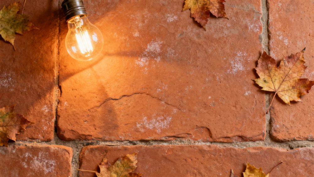 Pavimento de tijolos vermelhos com folhas de outono e lâmpada acesa a emitir luz quente