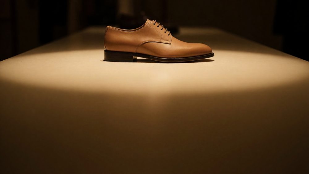 Sapato masculino castanho clássico em couro sobre superfície iluminada