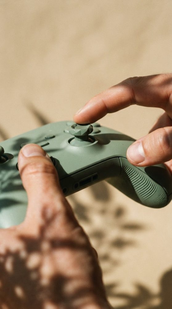 Mãos a manipular comando de videojogos verde com stick analógico