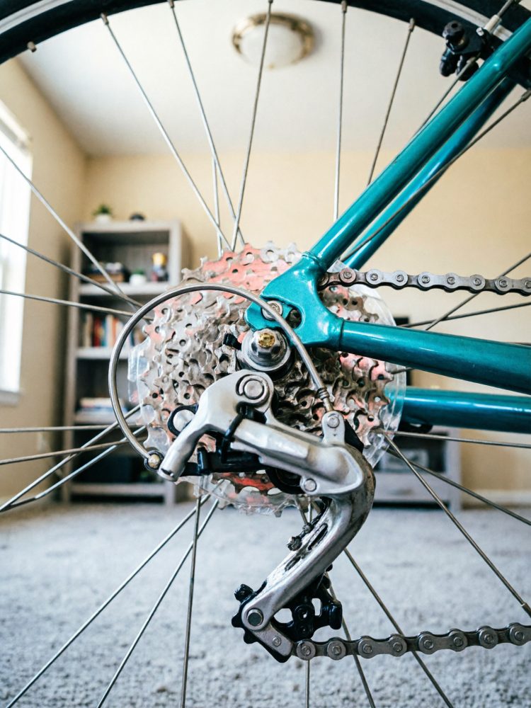 Detalhe do câmbio traseiro e corrente de bicicleta azul com fundo interior desfocado