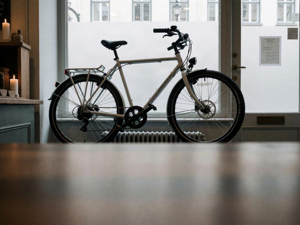 Bicicleta urbana branca encostada numa janela com velas e móveis rústicos ao lado