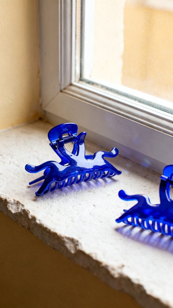 Prendedores de cabelo de plástico azul sobre peitoril de janela de pedra clara