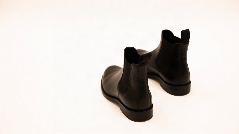 Par de botas Chelsea pretas minimalistas sobre fundo branco