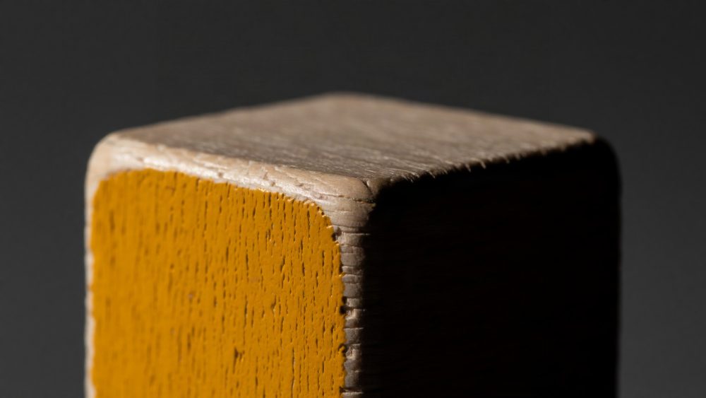 Close-up de bloco de madeira amarelo com textura e bordas arredondadas