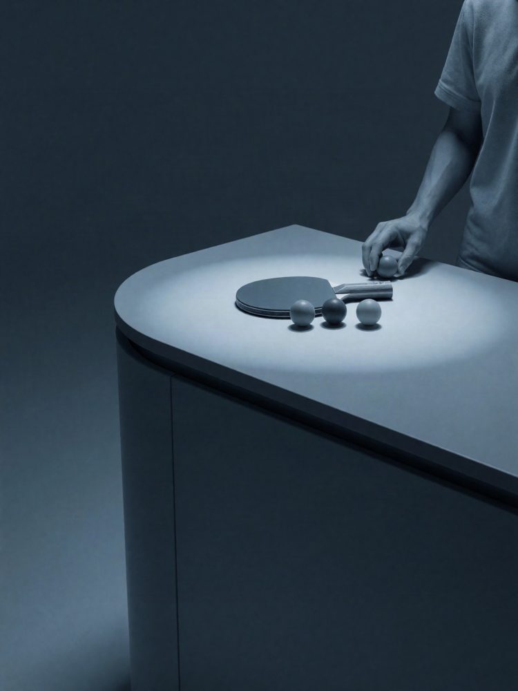 Raquete de ténis de mesa com quatro bolas e mão de jogador numa mesa branca