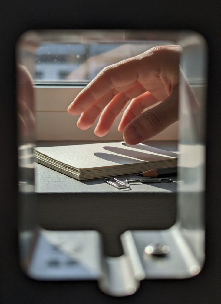 Mão a apanhar bloco de notas com clips metálicos e lápis recipiente sobre mesa iluminada