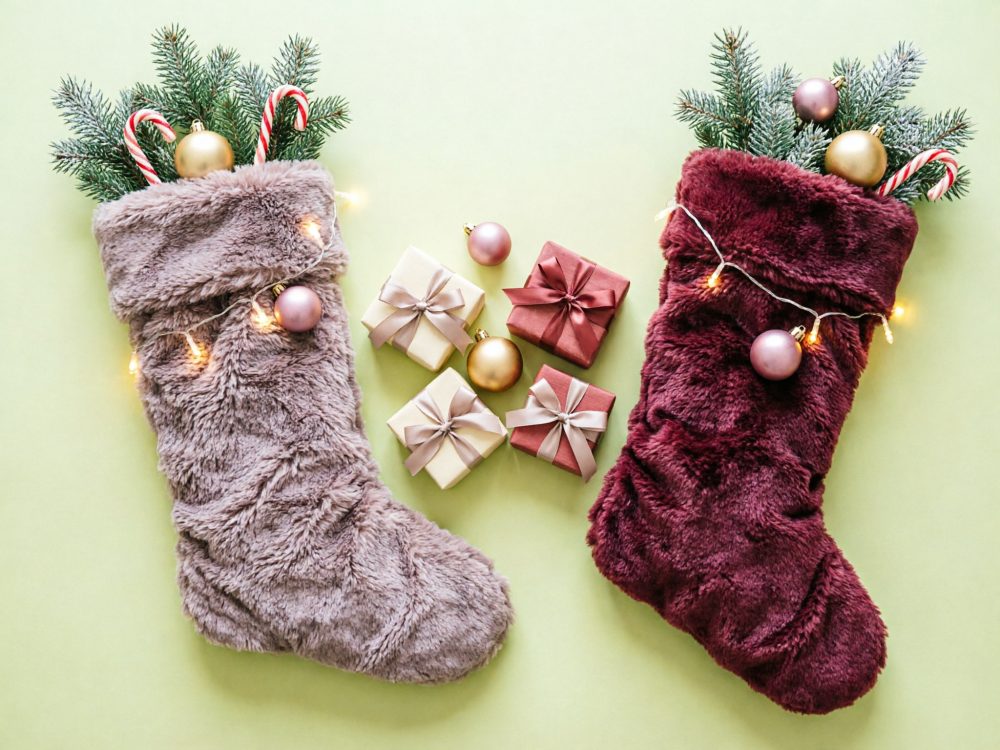 Duas meias natalícias felpudas com decoração festiva e pequenos presentes entre elas