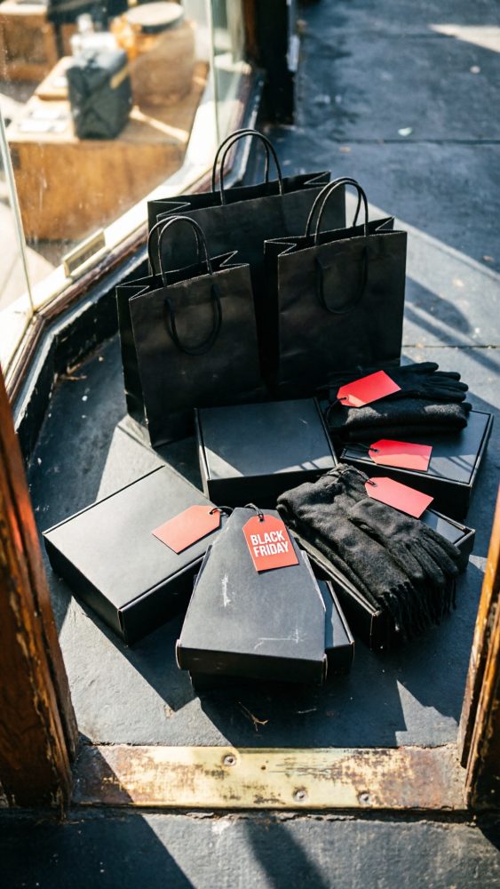 Embalagens e sacos pretos com etiquetas vermelhas a assinalar Black Friday numa montra urbana