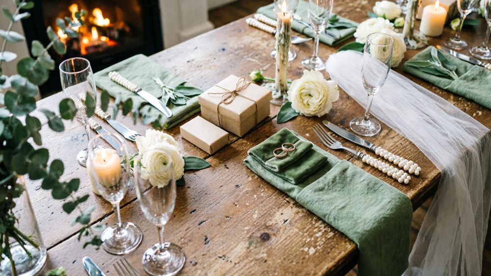 Mesa rústica decorada para casamento com flores, velas, guardanapos verdes e talheres com pérolas
