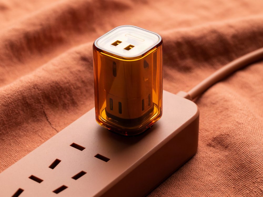 Carregador USB âmbar protegido numa régua de tomadas sobre tecido laranja
