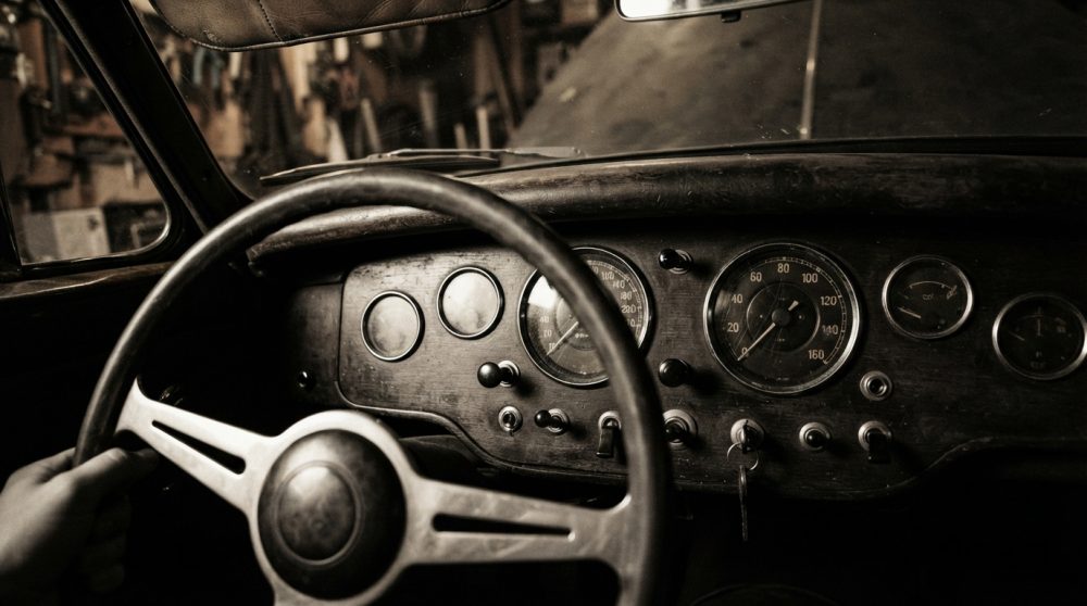Volante e painel analógico interior de carro antigo vintage com mão no volante