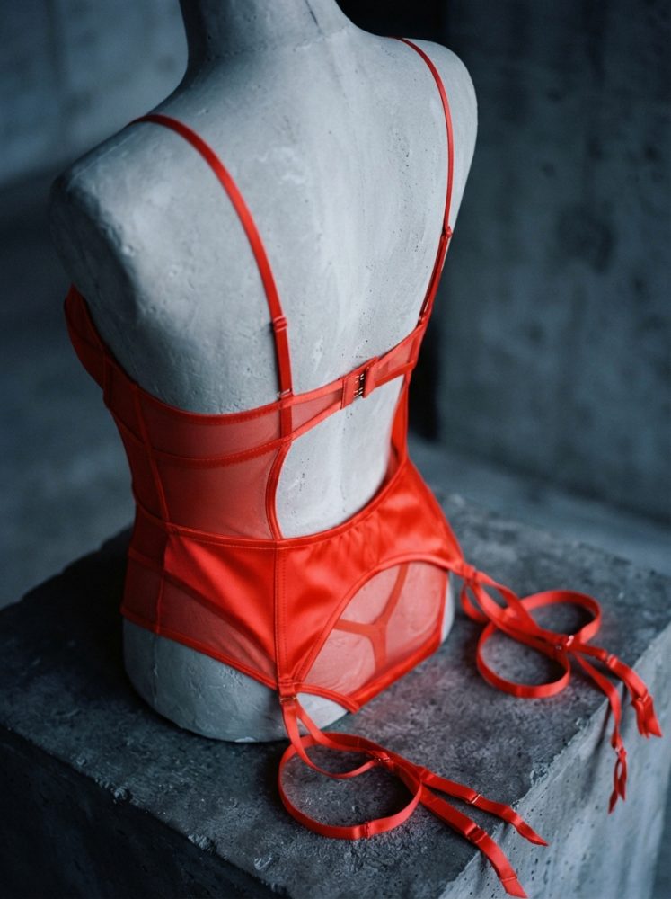 Conjunto de lingerie vermelho com cinta liga numa base de cimento