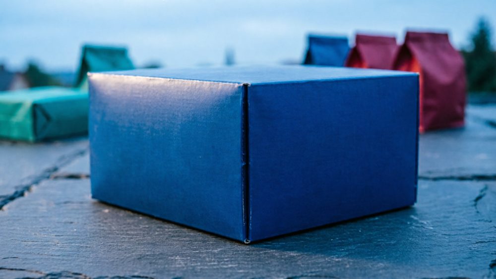 Caixa azul em destaque com várias caixas coloridas desfocadas numa superfície cinzenta
