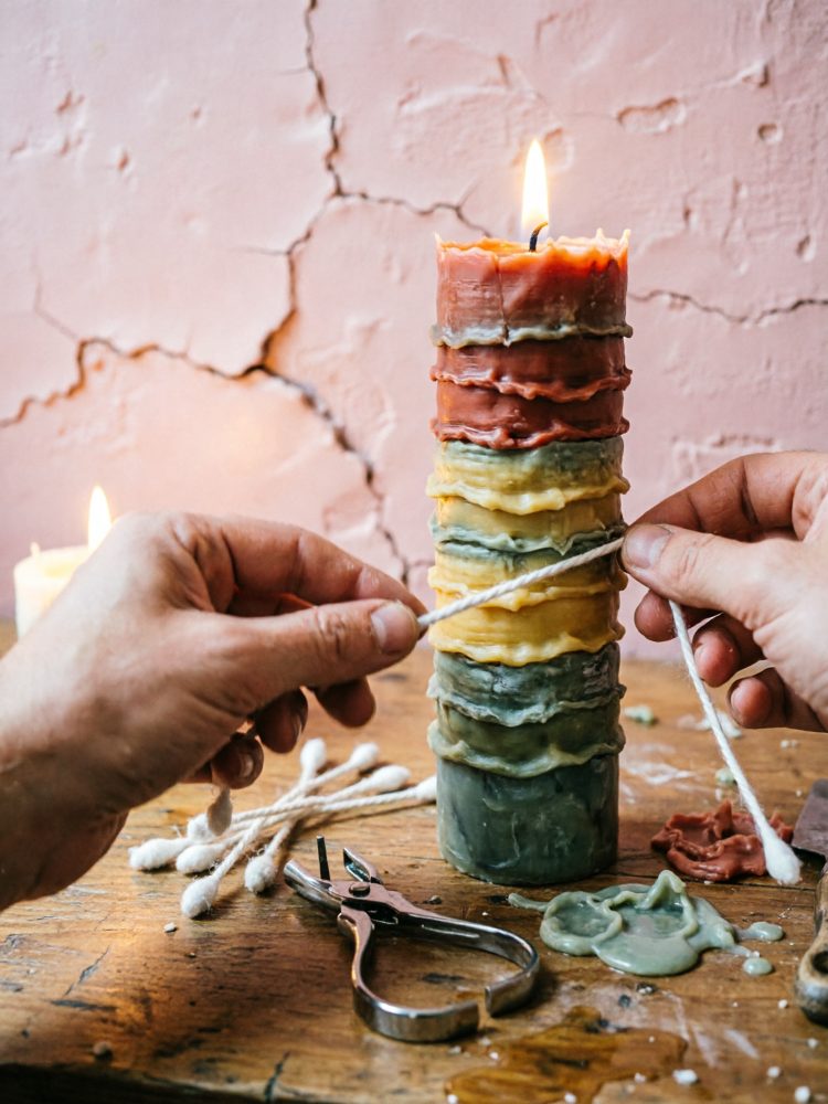 Vela artesanal colorida com diversas camadas e mãos a atar cordel