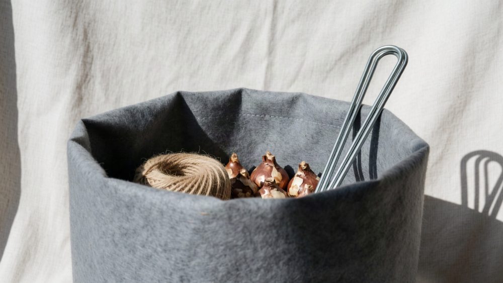 Saco cinza com bulbos de flores, corda e arames metálicos para jardinagem