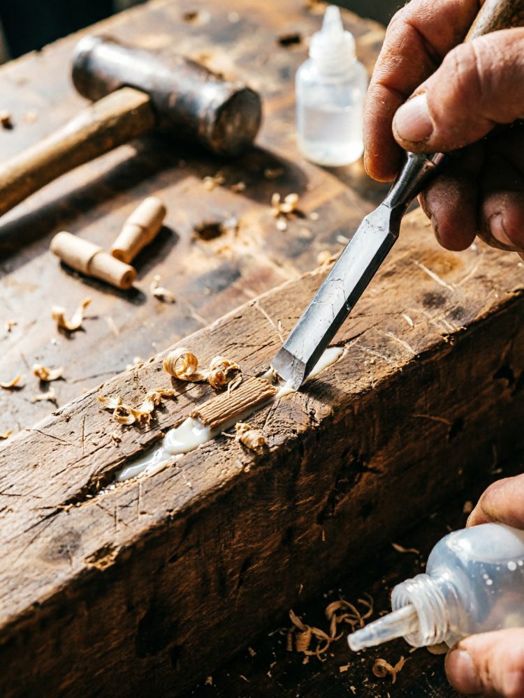 Mãos a reparar madeira com cola e ferramenta manual num atelier de bricolage