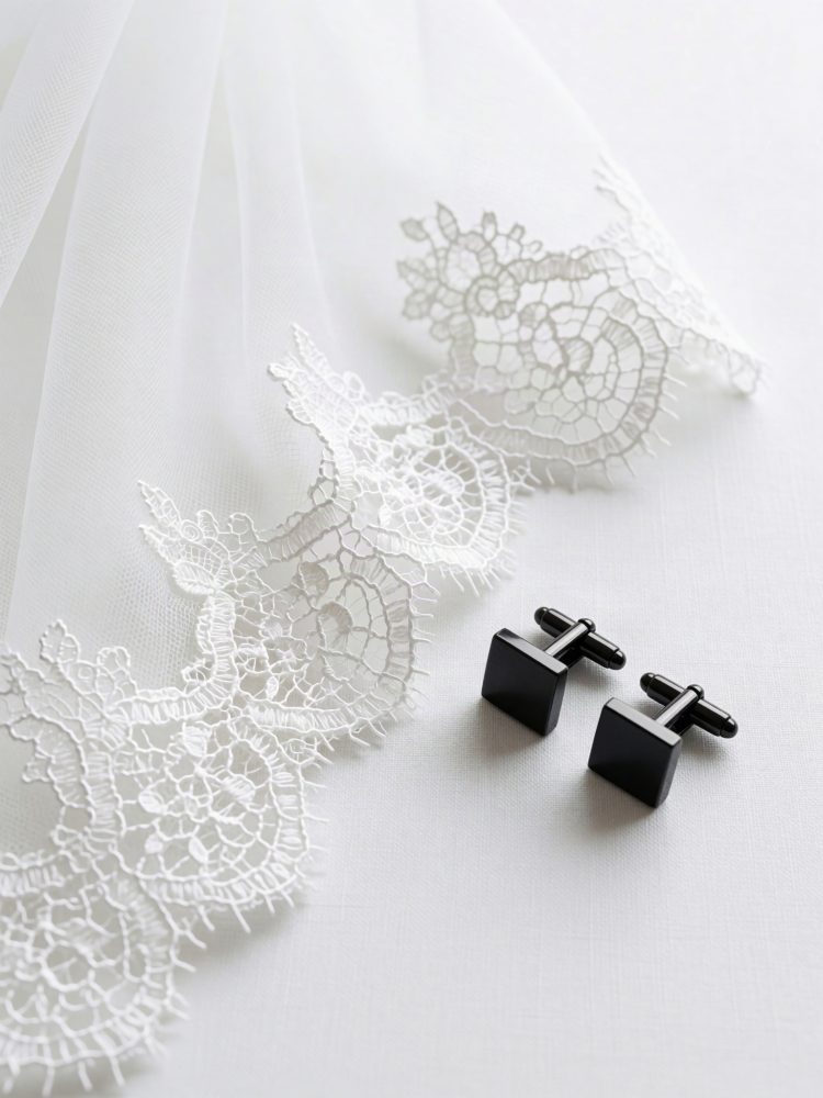 Botões de punho pretos sobre tecido branco com renda delicada branca para casamento