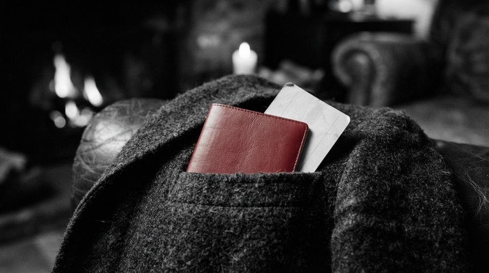 Porta-passaporte vermelho num casaco cinza escuro com bilhete, lareira ao fundo