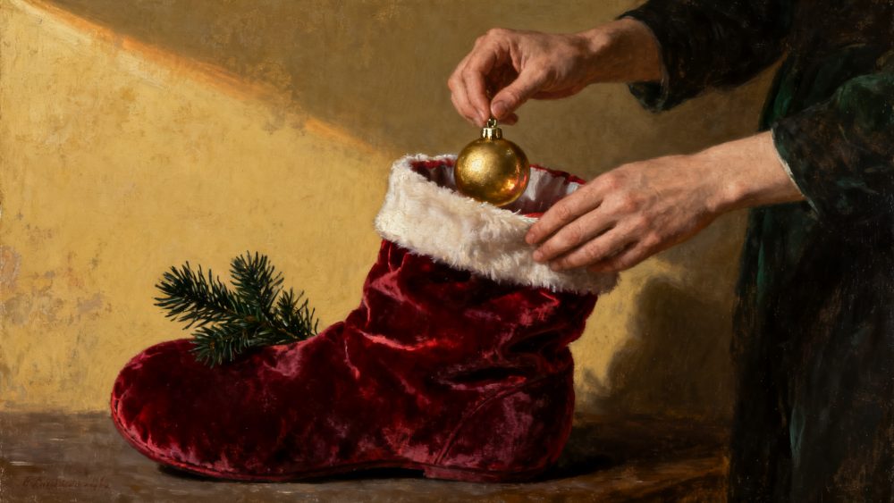 Mãos colocando ornamento dourado dentro de meia de Natal vermelha com ramo de pinheiro