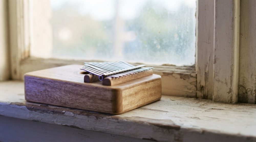 Kalimba de madeira em peitoril de janela antiga com vidro fosco e luz natural