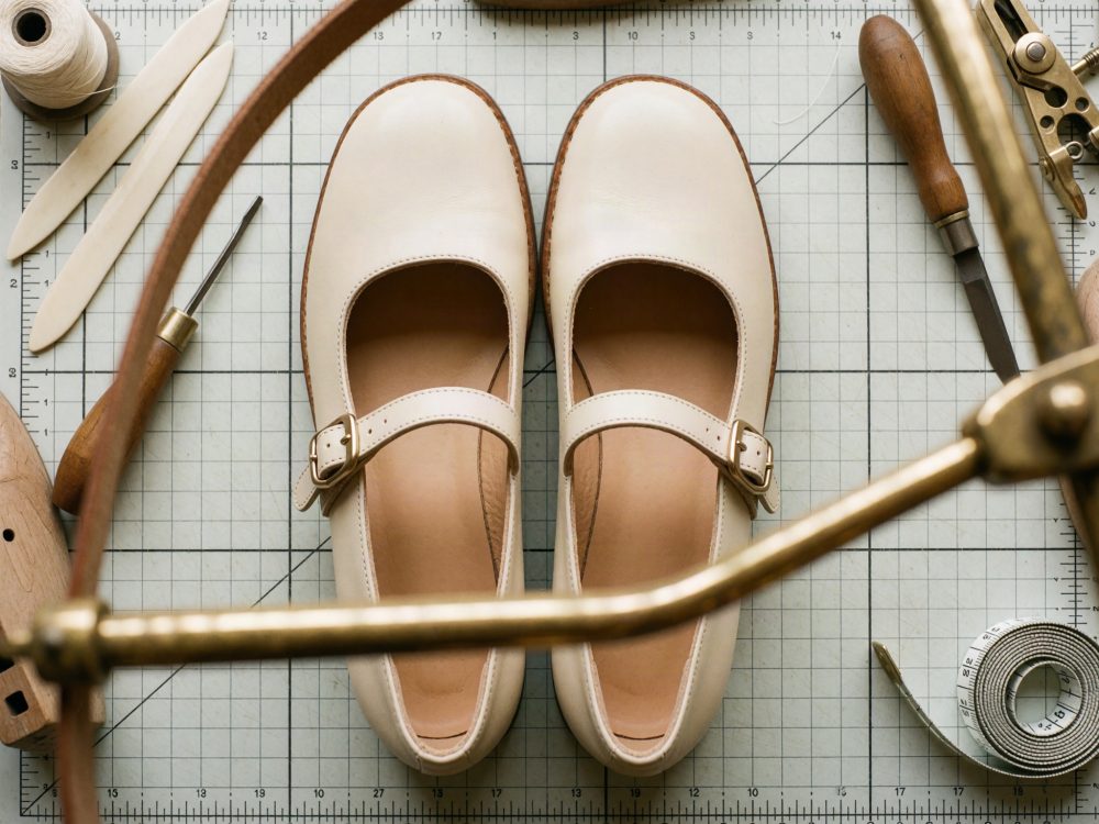 Sapatos creme Mary Jane e ferramentas de artesanato em superfície quadriculada