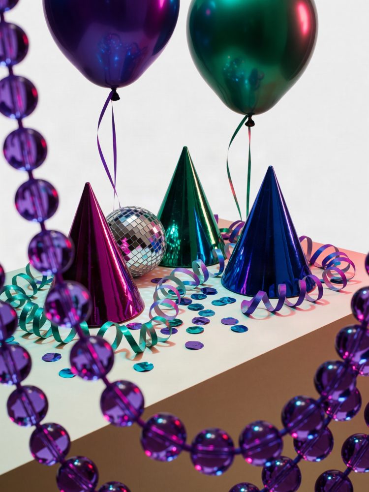 Chapéus metálicos coloridos, balões cintilantes, serpentinas e confetes azuis sobre mesa para festa