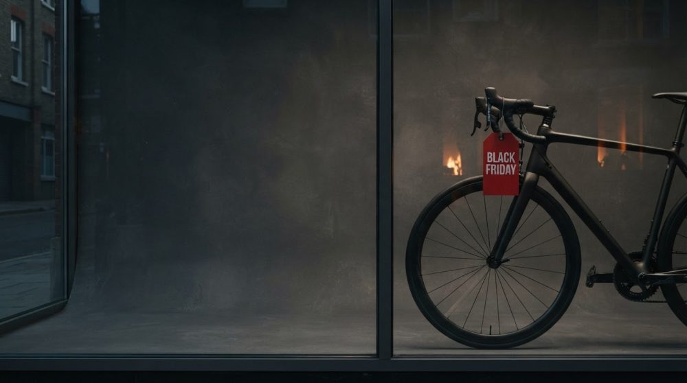 Bicicleta preta com etiqueta vermelha de Black Friday numa montra urbana com pouca luz