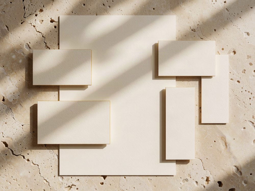 Conjunto de cartões e folha de papel texturizados sobre mesa de mármore com luz e sombra