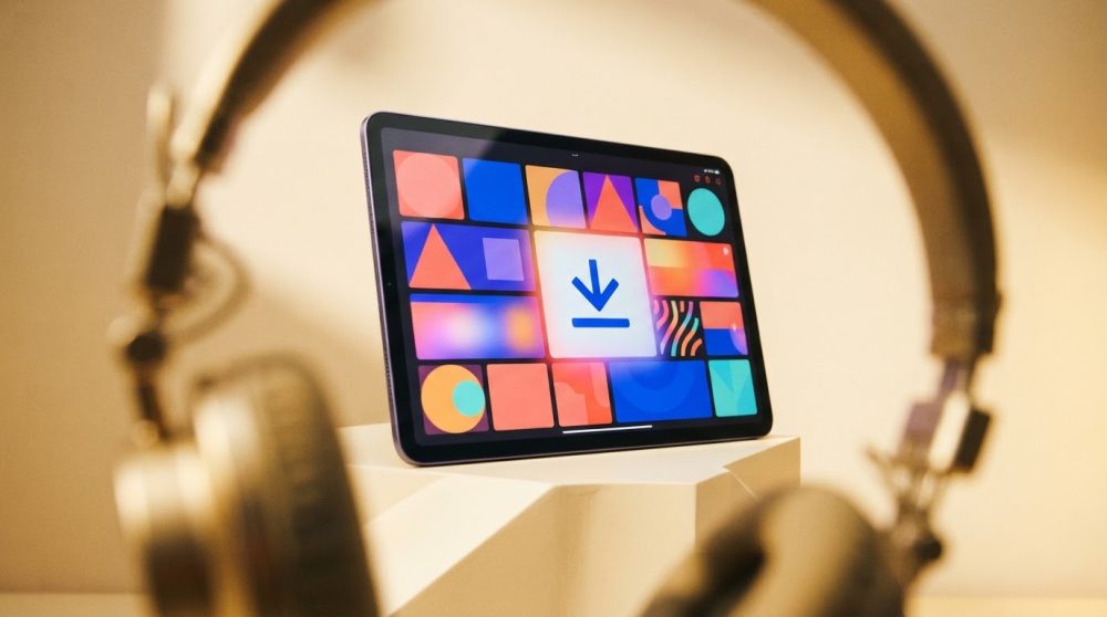 Tablet com ícones coloridos e símbolo de download, auscultadores dourados desfocados em primeiro plano