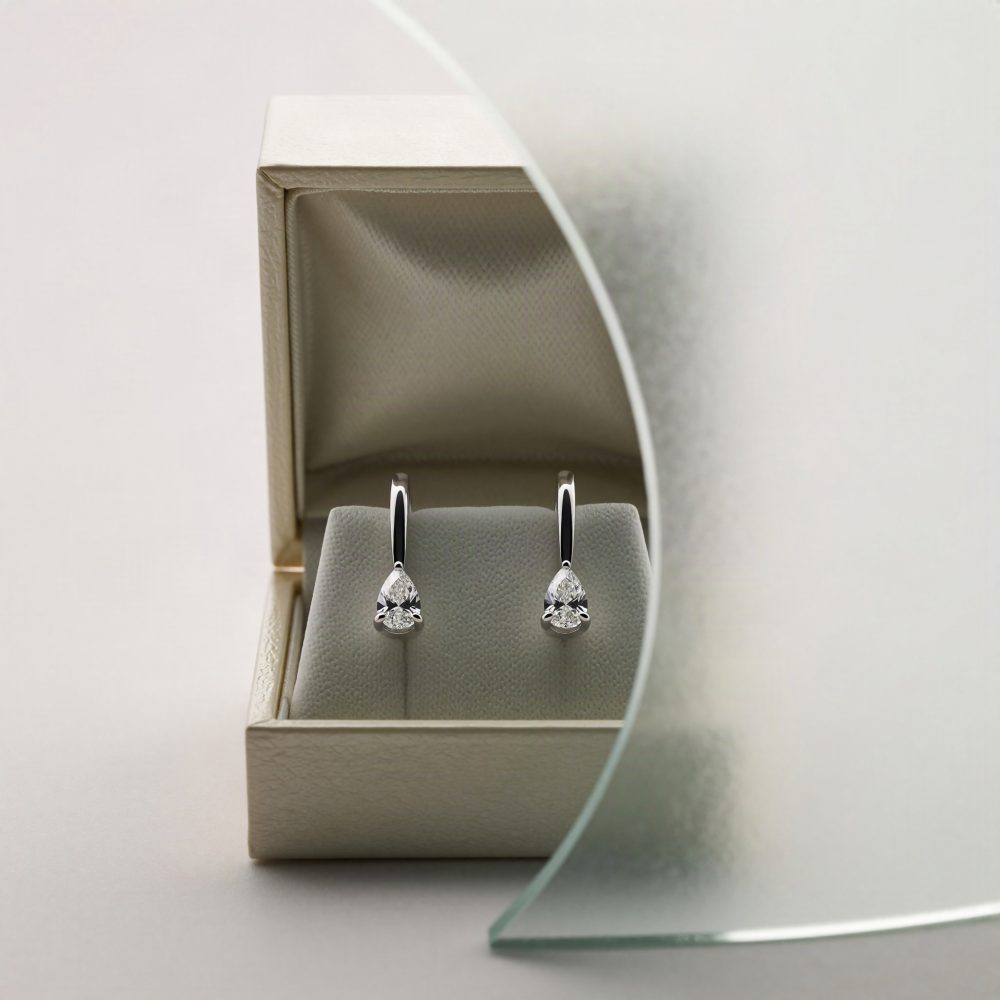 Brincos de prata com diamantes em forma de gota dentro de caixa branca elegante