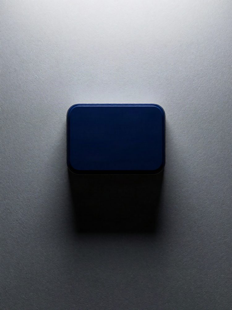 Caixa metálica azul vista de cima com sombra em fundo cinza texturizado