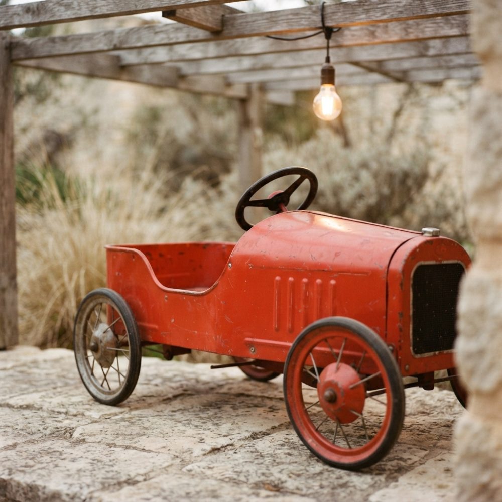 Carro de brinquedo vermelho clássico com volante e rodas finas sobre pedra