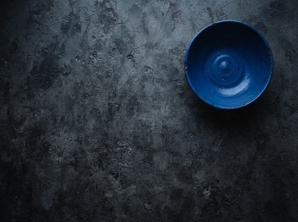 Prato azul sobre superfície escura rugosa com textura variada