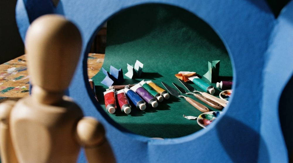 Tubes de tinta, espátulas, paletas e manequim de madeira, em estúdio de arte