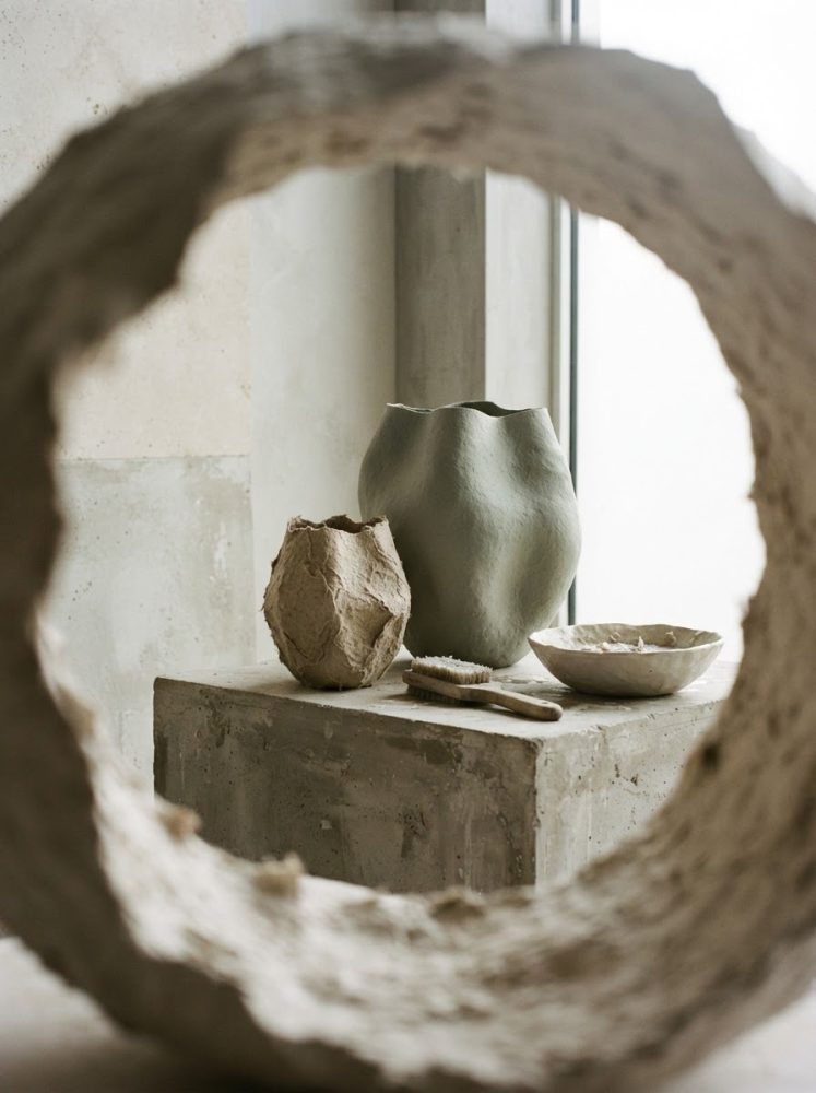 Conjunto de cerâmicas artesanais repousando numa base rústica vista através de um círculo texturado