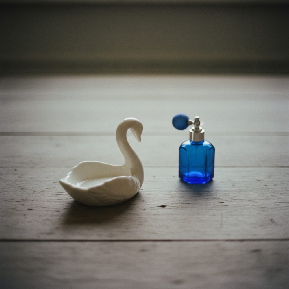 Frasco azul de perfume vintage e suporte branco em forma de cisne sobre madeira clara