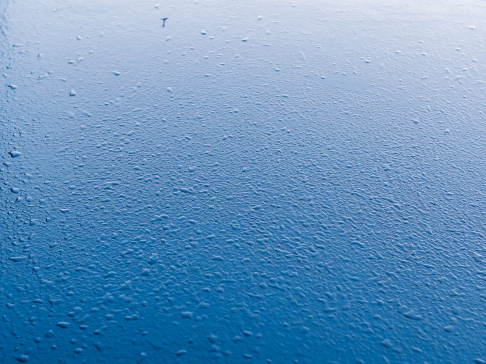 Superfície azul com gotas de água espalhadas refletindo luz natural