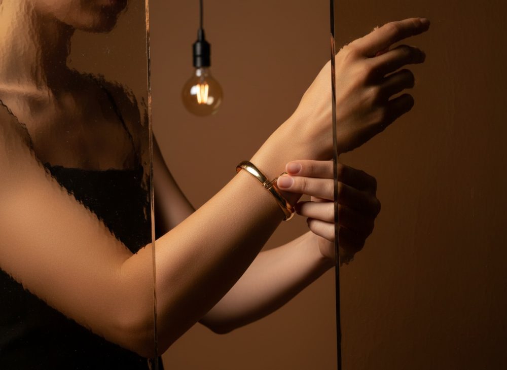 Braço feminino com pulseira dourada e luz ambiente quente