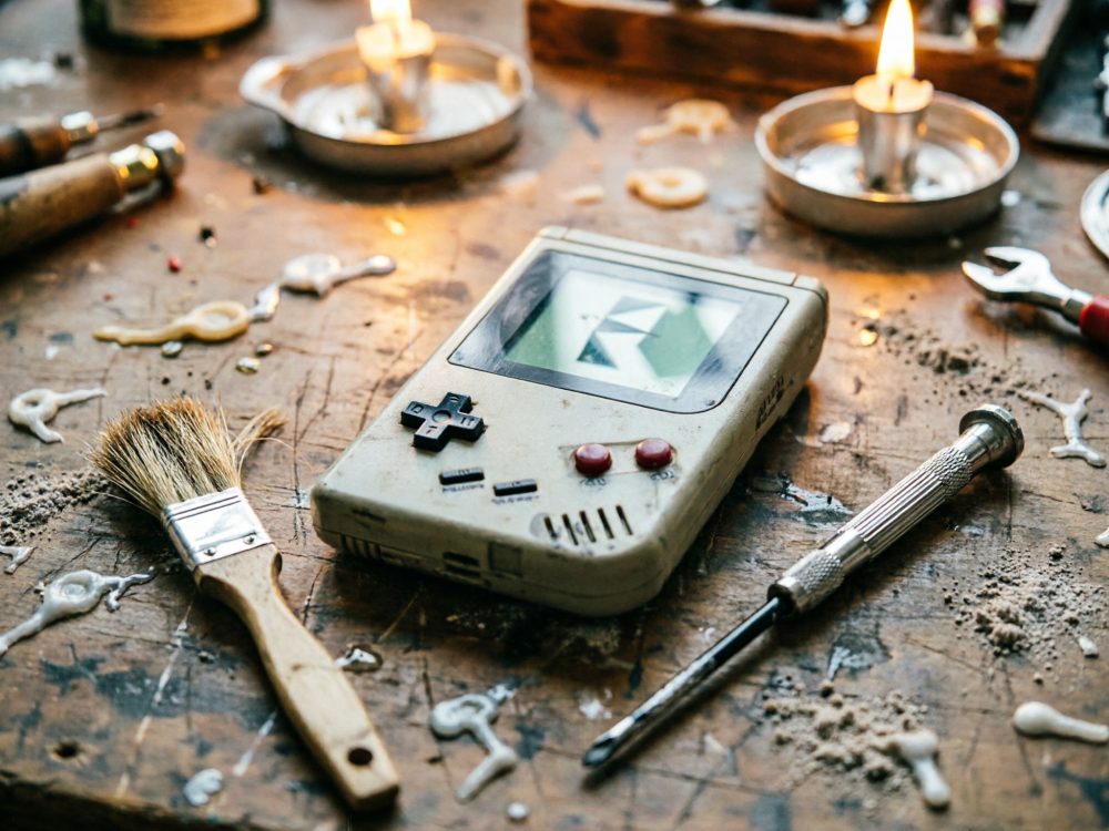 Consola portátil retro sobre mesa com ferramentas, pincel e cera derretida