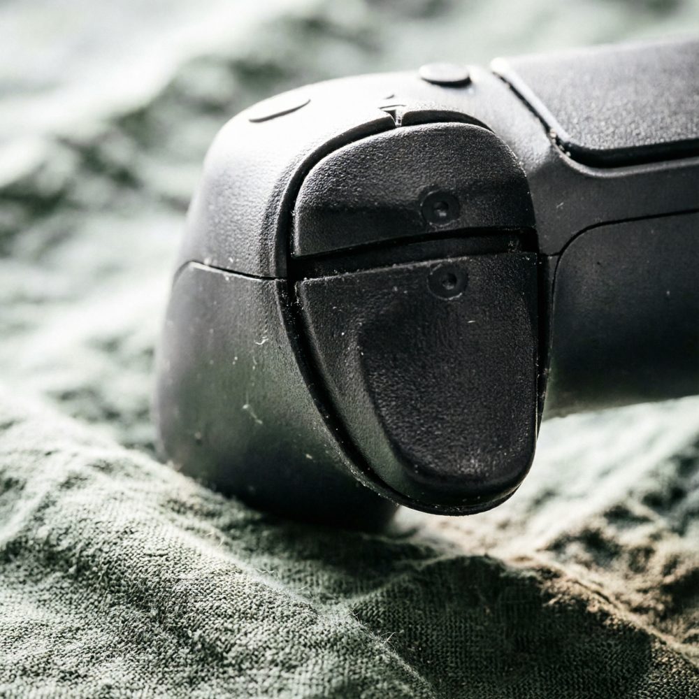 Botão traseiro de comando de consola preto sobre tecido verde com textura visível