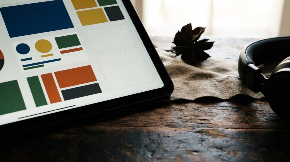 Tablet com gráficos coloridos sobre mesa de madeira com auscultadores e planta seca