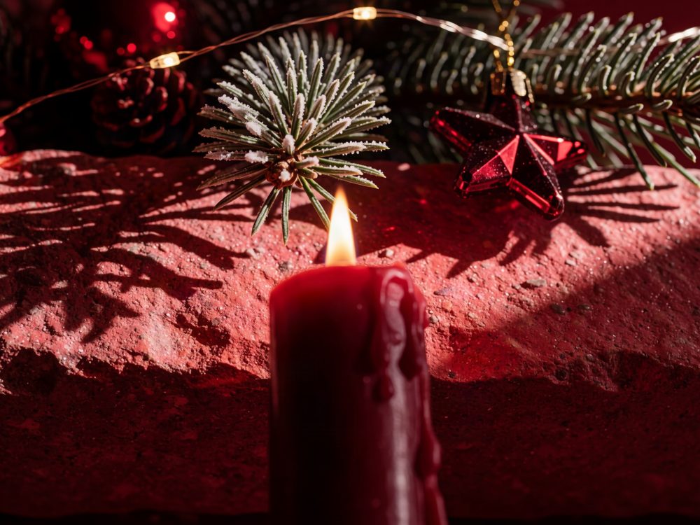 Vela vermelha acesa com decoração de pinheiro e estrela vermelha com neve artificial