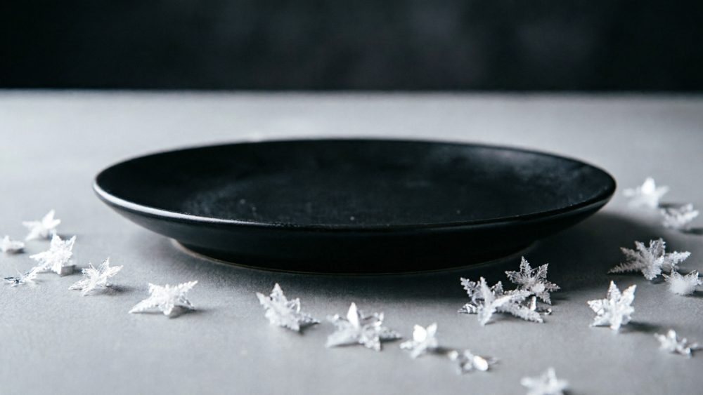Prato preto rodeado de estrelas brancas decorativas sobre mesa cinzenta