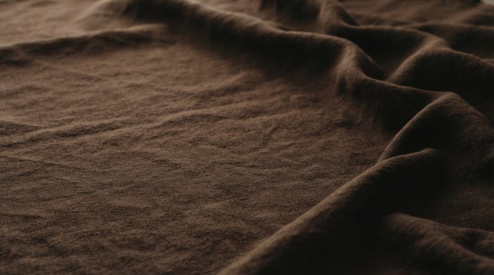 Superfície em tecido castanho escuro com textura e pregas naturais